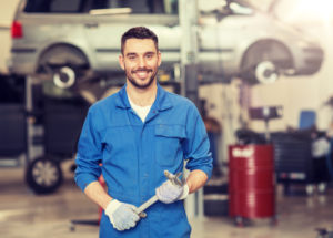 Mechanic smiling while working on a vehicle.